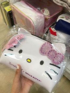 a hello kitty purse is being held up by someone's hand in a store