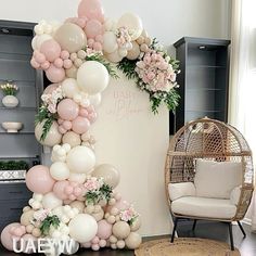 a balloon arch with flowers and greenery on the top for a baby's first birthday party