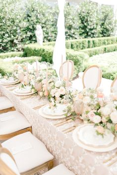 the table is set with white and pink flowers, gold chargers, and place settings