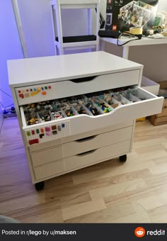 a white drawer with legos in it on top of a hard wood floor next to a chair