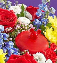 a vase filled with red, white and blue flowers next to a heart shaped cake