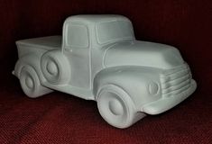 a white plastic toy truck sitting on top of a red couch next to a wall