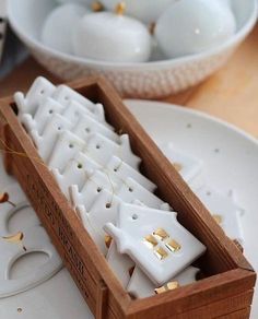 a wooden box filled with white candles on top of a table next to plates and bowls