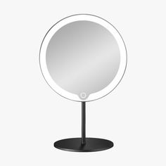 a round mirror sitting on top of a metal stand