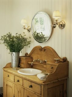 a bathroom with a sink, mirror and potted plant on the dresser in front of it