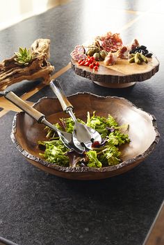 there are two bowls on the table with salad in them and utensils in each bowl