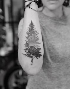 a woman with a bear and pine tree tattoo on her arm