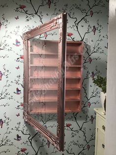 a mirror that is on the side of a wall next to a cabinet with shelves