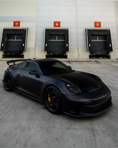 a black sports car is parked in front of some doors