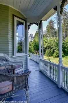 a porch with wicker furniture on it and trees in the backgroung