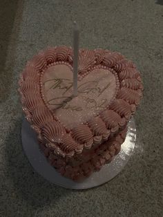 a heart shaped cake with a single candle in the middle on a counter top,