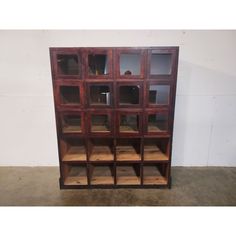 an old wooden bookcase with glass doors on the top and bottom shelves, in front of a white wall