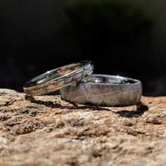 two wedding rings sitting on top of a rock