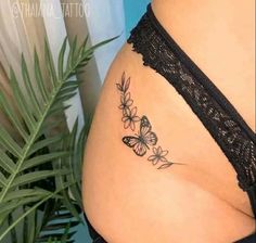 a woman's stomach with butterflies tattoo on the side of her belly and behind her is a potted plant