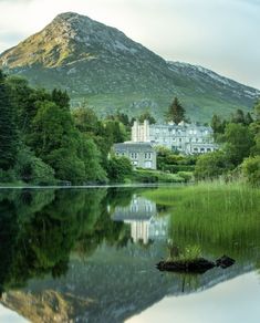 a large white house sitting on top of a lush green field next to a lake