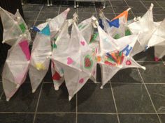 there are many kites hanging on the tile floor and one is white with multicolored designs