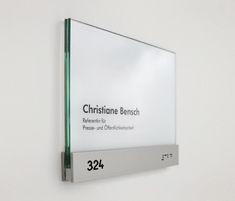 a glass sign mounted to the side of a white wall next to a metal frame