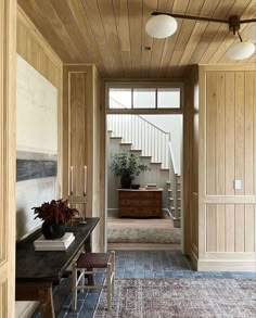 a hallway with wooden paneling and stairs leading up to the second floor is shown