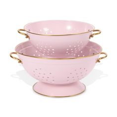 three pink colanders with gold rims and handles on each side, one is holding