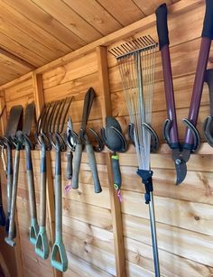 there are many garden tools hanging on the wall