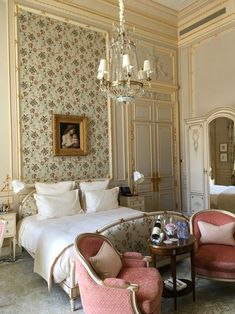 a bedroom with floral wallpaper and chandelier above the bed is decorated in pink