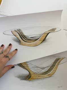 a woman's hand is pointing at two drawings on paper, each with different shapes and sizes