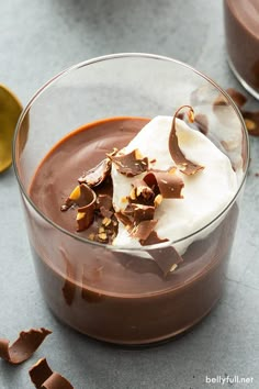 chocolate dessert with whipped cream and nuts in a glass bowl on a gray table top