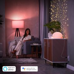 a woman sitting on a couch next to a night stand with a lamp in the corner