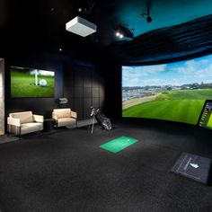 a golf simulator with two monitors and chairs