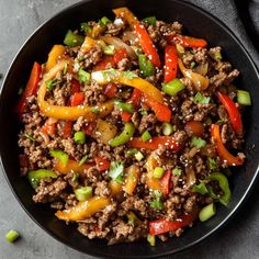 a black bowl filled with ground beef and peppers on top of a gray tablecloth