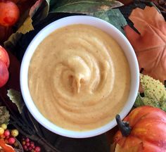 a white bowl filled with peanut butter surrounded by fall leaves