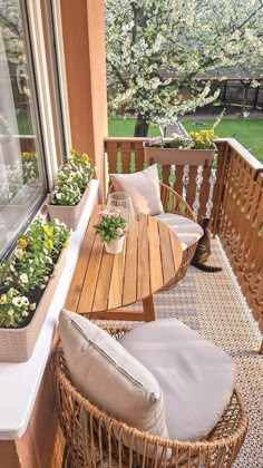 a wooden table sitting on top of a porch next to a window filled with flowers