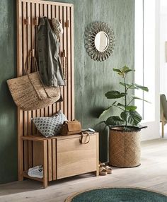 a wooden bench sitting next to a plant in a room with green walls and wood flooring