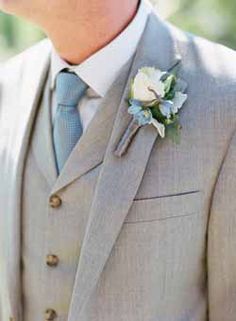 a man in a gray suit with a boutonniere on his lapel