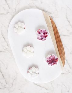 a white plate topped with paw prints next to a wooden spoon on top of a marble counter