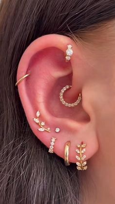 an ear with three different types of piercings on top of the ear and one is gold