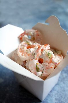 a small white box filled with food sitting on top of a blue tablecloth covered surface