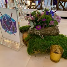 the table is set with flowers and moss