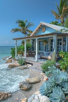 a house sitting on top of a sandy beach next to the ocean with palm trees