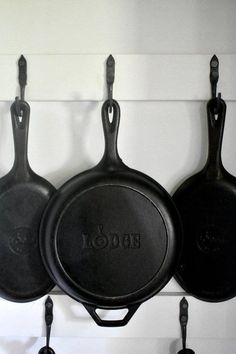 three cast iron skillets hanging from hooks