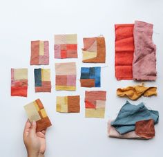 several pieces of cloth laid out on a table with one hand holding a piece of fabric