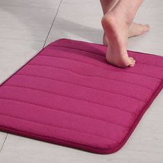 a person standing on a pink mat with their feet in the floor next to it