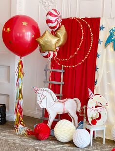 red and white balloons are on the floor next to a horse, rocking chair, and other decorations