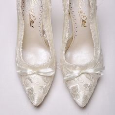 a pair of white wedding shoes with bows on the toe and lace detailing are shown