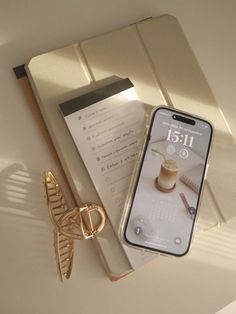 a cell phone sitting on top of a table next to a pair of gold scissors