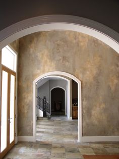 an archway leading into a room with stone flooring and walls painted in shades of beige