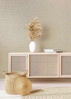 a white vase sitting on top of a wooden cabinet next to a basket and rug