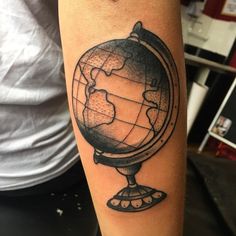 a black and white photo of a globe tattoo on the arm