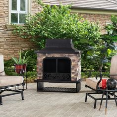 an outdoor fireplace sitting on top of a patio next to two chairs and a table