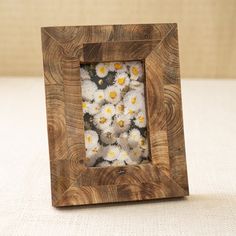 a small wooden frame with daisies in it